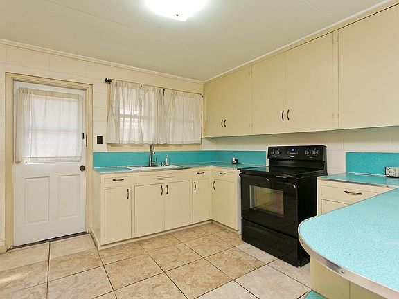 Well cared for Retro kitchen. The backdoor leads out to the patio and laundry