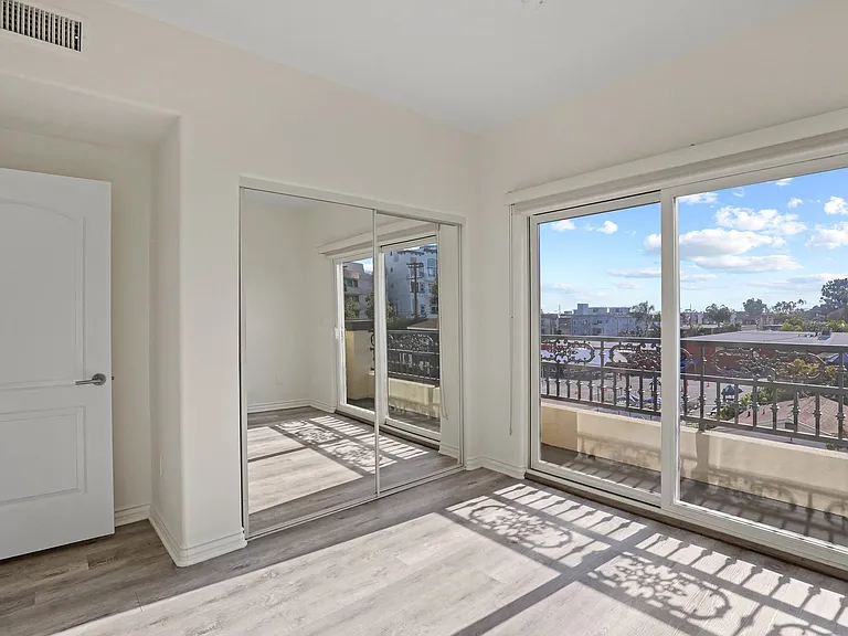 Bedroom with Mirrored Closet, Private Balcony, and Vinyl Flooring