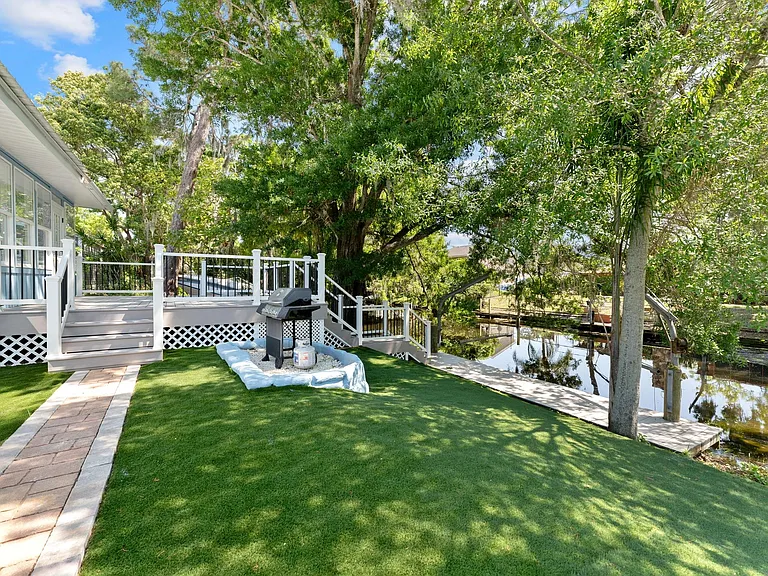 Raised deck with steps to a landscaped yard and waterfront walkway, plus an outdoor grill area for easy entertaining.