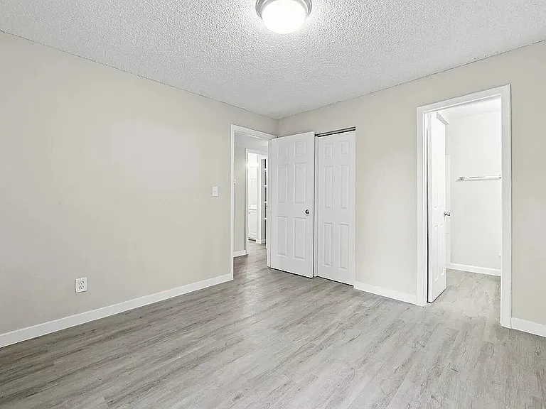 Bright and airy bedroom with sleek wood flooring, ample closet space, and a stylish white interior.