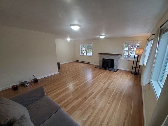 Living room with newly refinished floor, wall section left of bricks reframed for slider window with rock wool insulation and new siding, black walnut live edge slab mantel and trim around new hearth tiles, and colors chosen for...muted sophistication.