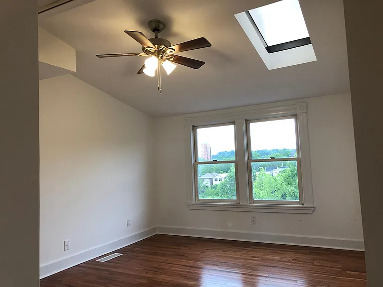Bedroom with skylight, window with view and hardwood floor.