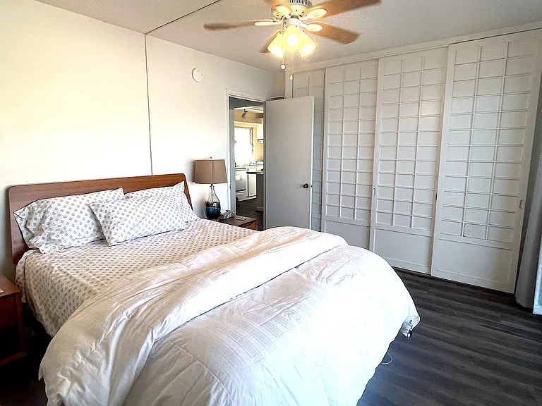 Cozy queen bed and two nightstands provided. This photo shows doors to living room slid shut for privacy.