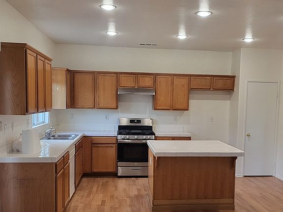 Kitchen with dishwasher, stove/oven range, and island with bar seating.