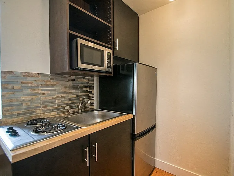Chic kitchenette with modern appliances and stylish tile backsplash, perfect for efficient cooking.