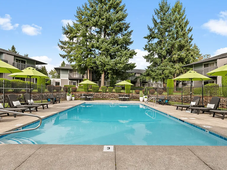 Resort-style swimming pool with relaxing lounge seating and lush surroundings.