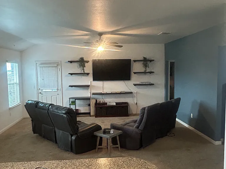 Furnished living room with 65 inch Tv and two reclining couches