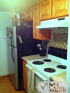Kitchen with newer wood cabinets, custom tile backsplash behind stove, and corian countertops and br
