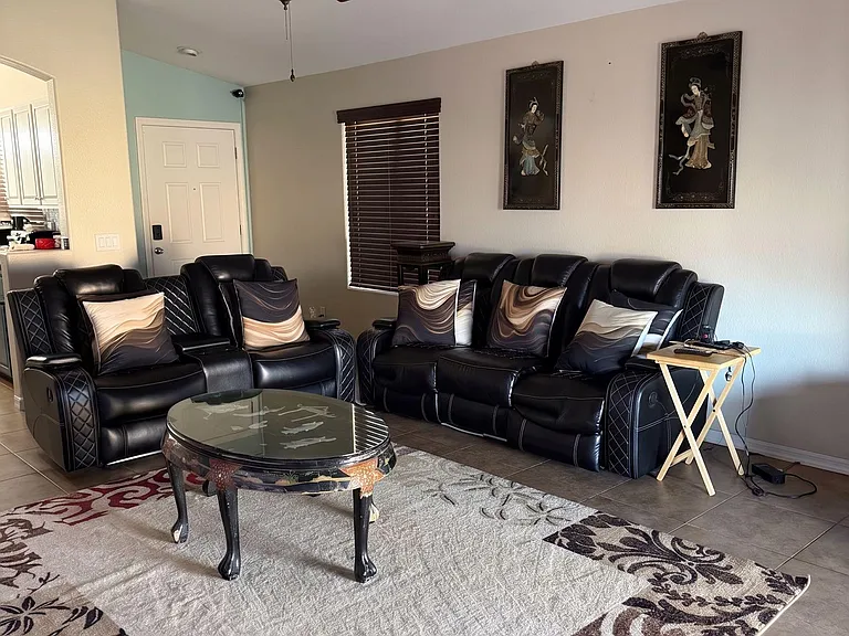 Living room with sectional seating, ceiling fan, and a large window with blindsideal for relaxing or shared hangouts.