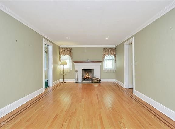 The living room is very spacious and features a wood burning fireplace, hardwood floor with beautiful border and crown molding.