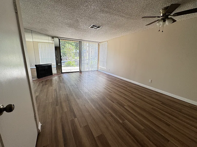 Full Open Living Room with a fan situated to have a dining area or open entertainment space. Floor to ceiling mirrors brighten up the space and a fireplace for cozier nights