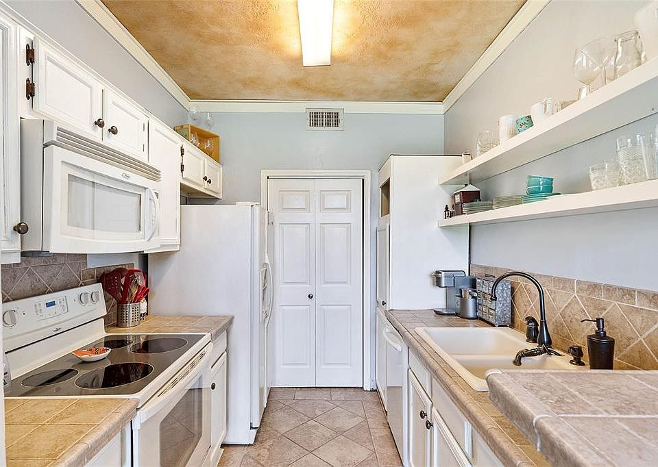 The kitchen has an electric range and access to the utility closet. There is ample cabinet and counter space.