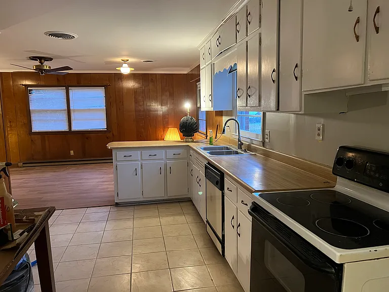 Kitchen and many, many cabinets. 
All freshly painted. Looking into paneled den with new Luxury Vinyl Plank.