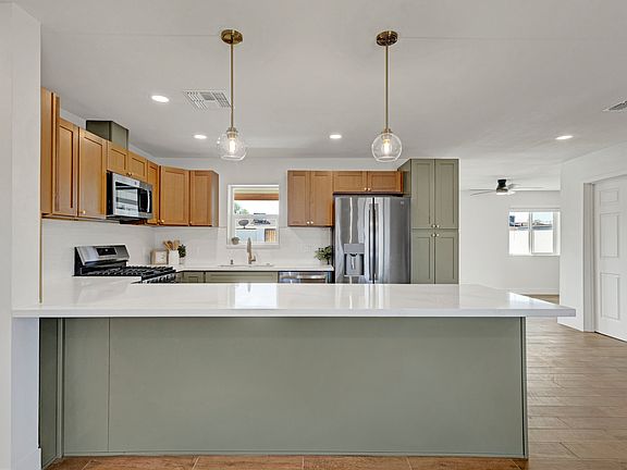 Stunning Renovated Kitchen _ Featuring custom cabinetry, stainless steel appliances, a spacious quartz peninsula with breakfast bar, and a gas range for a chef-inspired cooking space.