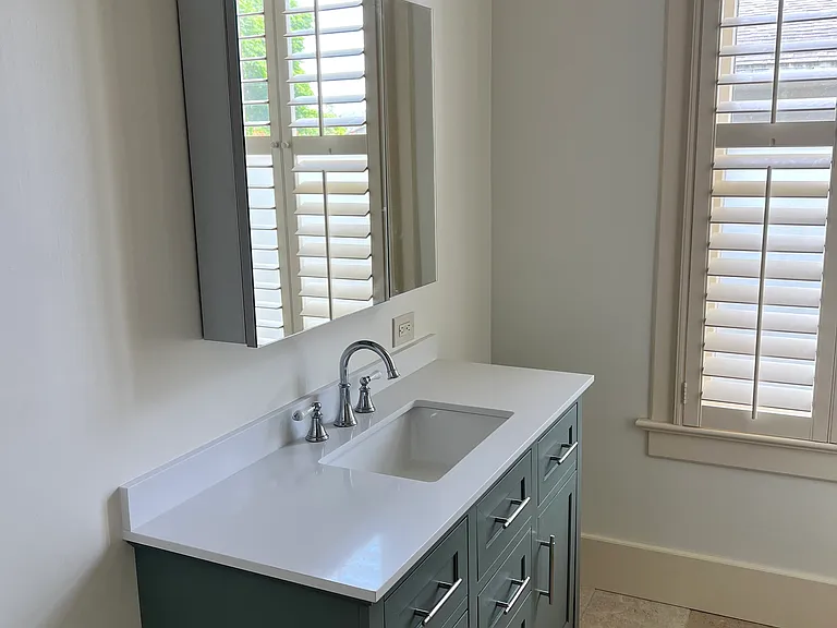 Newly updated bathroom - travertine tile, tiled tub/shower, new vanity and medicine cabinet, accent lighting, plantation shutters.