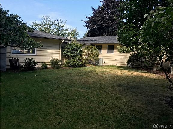 Lawn in back yard is big enough for croquet and other games. Double garage on left, back of house on the right.
