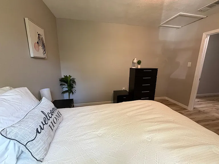 Furnished bedroom with a full bed, dresser, and nightstand, plus wood-look flooring and neutral paint for easy decorating.