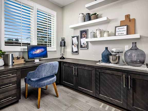 A cozy and well-organized home office space with dark wood cabinets, shelves displaying decorative i