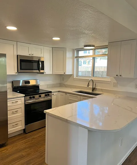 KITCHEN WITH NEW CABINETS, SS APPLIANCES AND SLAB QUARTZ COUNTERTOPS.