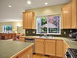 ...tiled countertops, maple cabinets and stainless steel appliances.