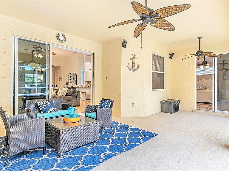 Covered patio with ceiling fans, outdoor seating, and sliding glass doors offering easy access to the main living area.