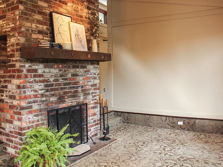 Cozy sunken living room with unique floor to vaulted ceiling fireplace with built-in display alcoves