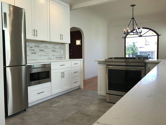 Fully remodeled kitchen with updated appliances (including stackable washer/dryer in separate hallway), quartz countertops, marble backsplash, and tile flooring that open up to the dining room with it's updated chandelier!