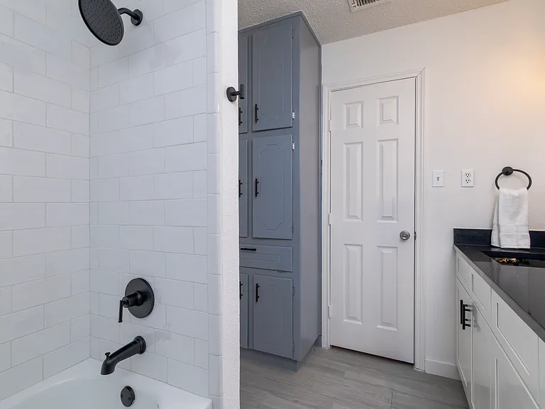 Full bathroom with double sinks and shower-tub combo attached to bedroom 1.