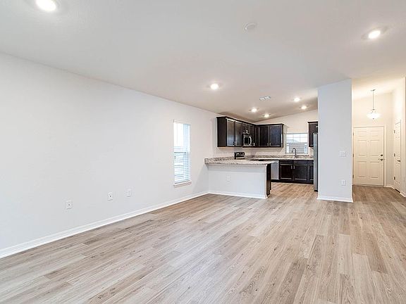 Enjoy a sunny, open living area with volume ceilings and vinyl plank flooring - New home for sale in