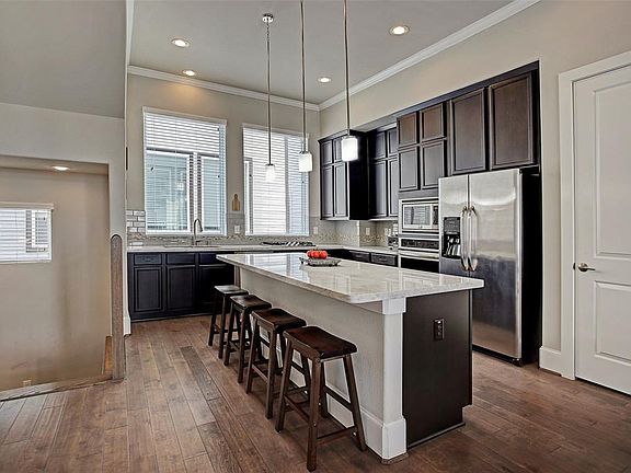 Immaculate kitchen has tons of storage space! A truly elegant kitchen with marble counters, custom tile backsplash, stainless appliances and contemporary pendant lighting.