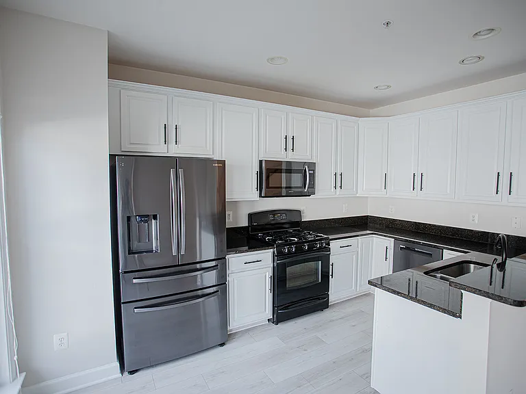 Modern Sleek Kitchen featuring granite countertops and updated stainless steel appliances. Gas stove and functional fridge