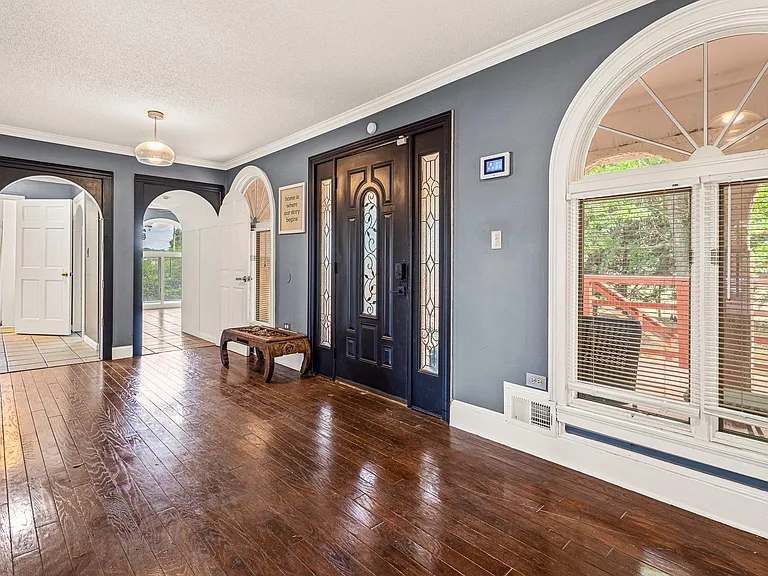 Welcoming entry foyer with hardwood floors, decorative front door, and an arched window that brings in natural light.