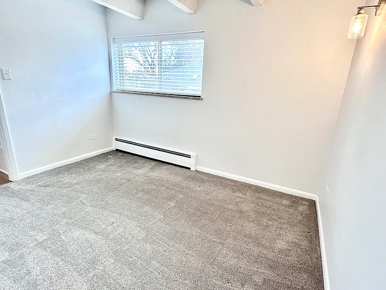 Bright and inviting room with plush carpet, large window, and elegant exposed beams. Bright and inviting room with plush carpet, large window, and elegant exposed beams.