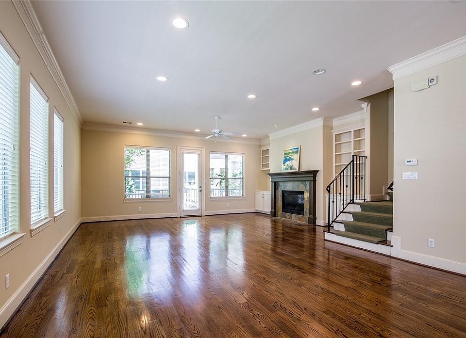 Living room with a gas fireplace, hardwood floors and windows all around has access to a small balcony.