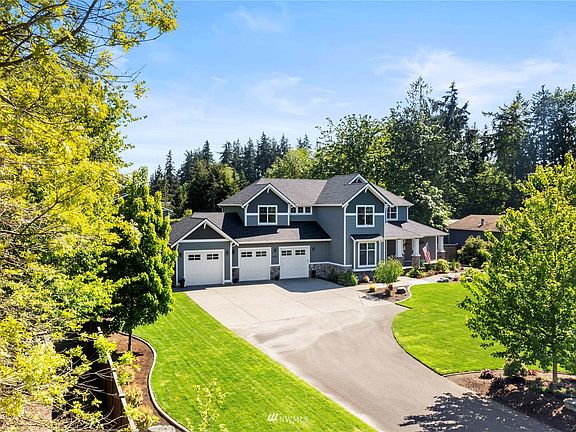Stroll past the impeccably manicured landscaping to the sprawling covered front porch anchored with stone-wrapped pillars.
