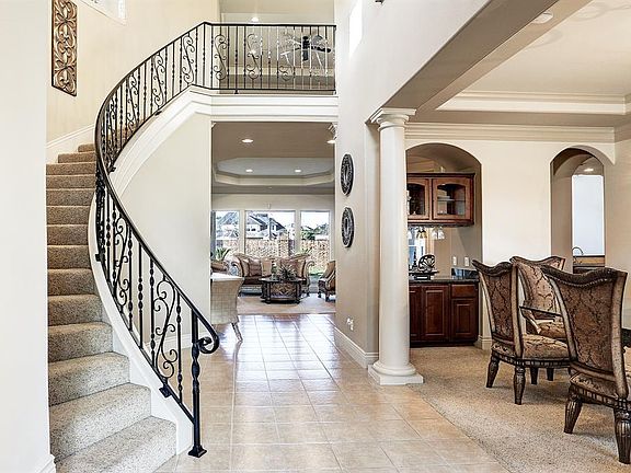 Breathtaking views of the sweeping staircase with elegant wrought iron balusters. The entrance hall opens up to the formal dining room with tiled flooring flowing through to the formal living area.