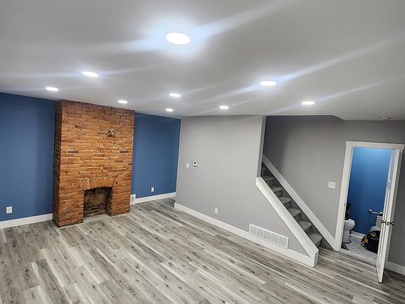 Living room with powder room access. Recessed lighting, decorative exposed brick fireplace (original), steps to master bedroom