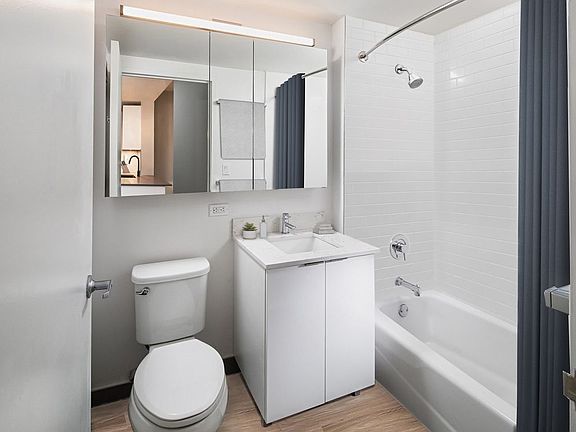 Renovated Package I bath with white marbled quartz countertops, white cabinetry, and hard surface flooring (representative image)