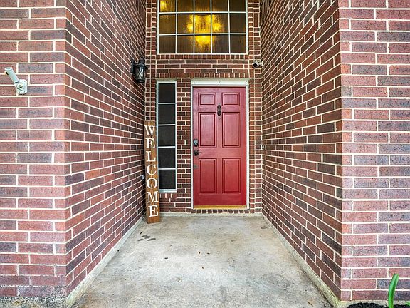 The bold red front door is a beacon welcoming you to your future home! From the covered porch we get a glimpse of one of the updated chandeliers in the foyer beyond. The security camera connects into the home where the study is.