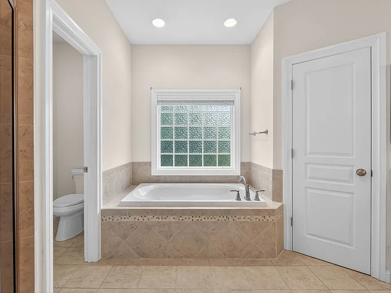 Primary linen closet with dual shower heads, soaking tub and private water closet