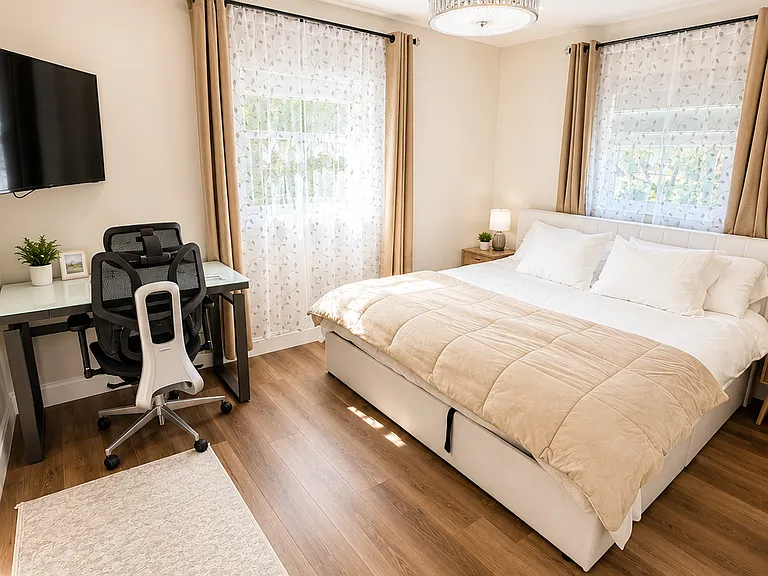 Bright primary king bedroom with fresh linens, smart TV, dedicated workspace, natural light, updated finishes, and a comfortable layout for long stays or remote work.