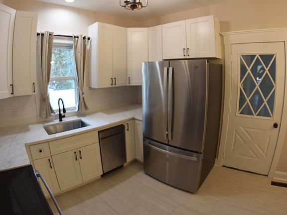 Newly renovated eat-in kitchen with stainless steel appliances, white shaker cabinets, and quartz counter tops