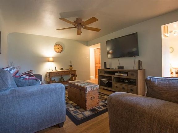 15x11 living room with hardwood floors, fresh paint, and newer ceiling fan.
