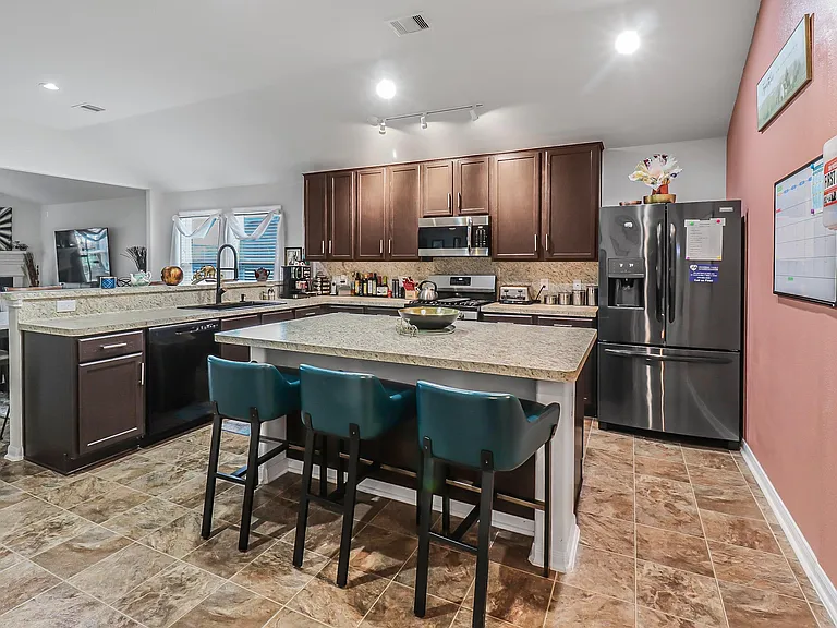 Open kitchen with a large island, bar seating, ample cabinetry, and stainless-steel appliances for everyday cooking.