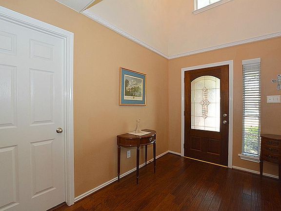 Large entryway welcomes guest and provides the first view of the gorgeous hand scraped wood floors. Door on left leads to laundry room and garage