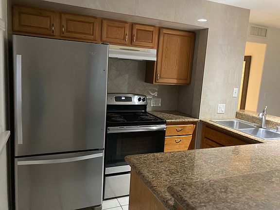 Stainless steel refrigerator, electric stove/oven/diswasher across from stove. Stainless steel double sink