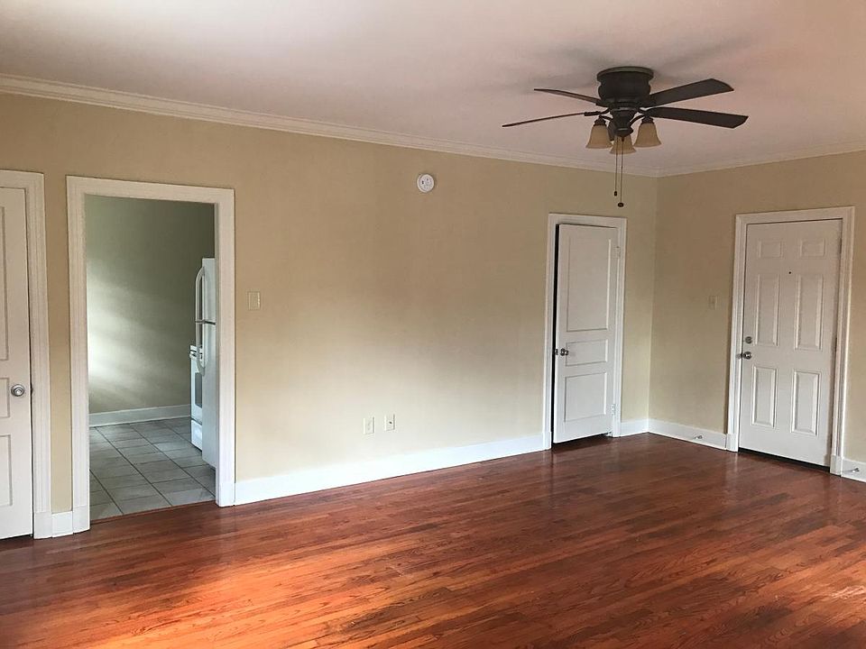 View of main room with beautiful hardwood floors looking into the kitchen. The door on the left is a coat closet, the middle door goes into the bathroom, and the door on the right is the exterior door.