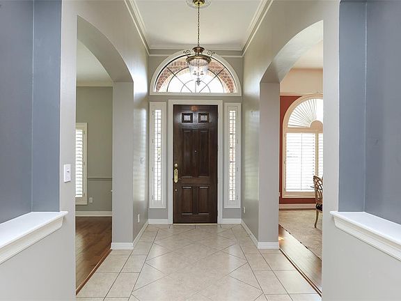 Entry with a high ceiling and crown molding is flanked by the formal living and dining rooms