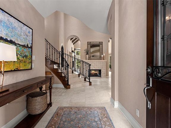 Open and spacious foyer with curved iron staircase, double sided fireplace is warm and welcoming.
