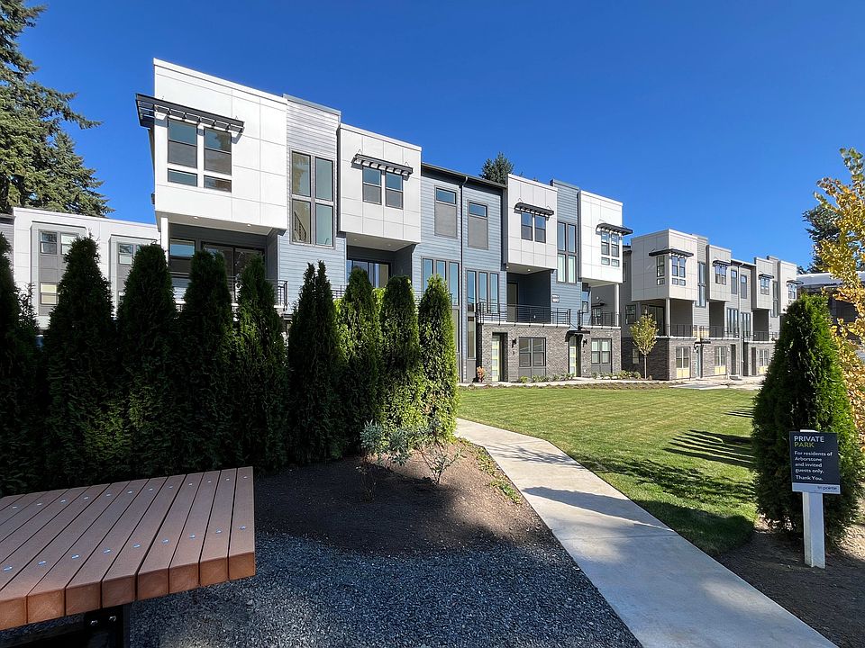 A modern, multi-story residential complex with a well-maintained landscaped area in the foreground,